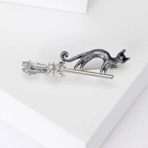 Close-up of black cat riding a silver broomstick brooch with sparkling crystal detail