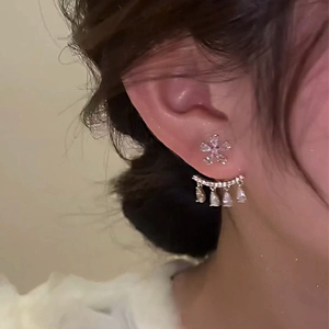 Detail of floral earring with teardrop tassel and zircon on a model in warm light
