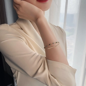 Détail du bracelet double chaîne dorée vintage avec perles vertes au poignet du mannequin
