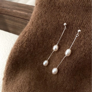 Detailed view of sterling silver chain earrings with natural freshwater pearls on fabric