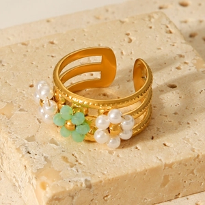 Detailed close-up of golden stainless steel ring with pearl and green beads on stone