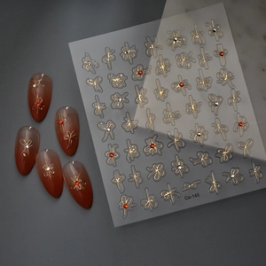 5D gold bow nail art stickers with red crystal gems and metallic finish on model