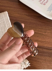 Detail of brown marble heart hair claw with transparent spiral spring grip held by hand