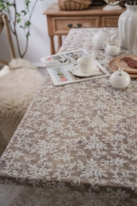 Detailed view of white floral lace embroidery on semi-transparent fabric tablecloth