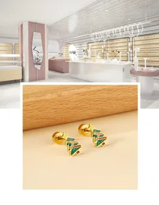 Close-up of golden Christmas tree earrings with green oil drip and glitter details