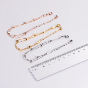 Double-layered snake chain bracelet with square charms in gold, silver, and rose gold