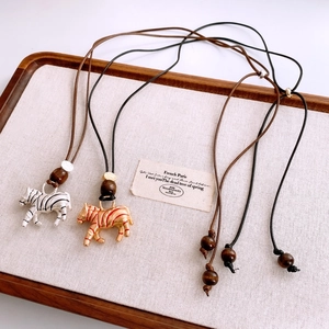 Detail of zebra pendant necklaces with wood beads on adjustable leather cords