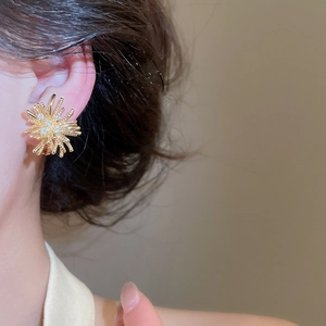 Detailed close-up of a elegant 18k gold-plated zircon firework clip-on earring on a model's ear.