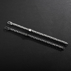 Detail of silver and black stainless steel box chain bracelets on black leather