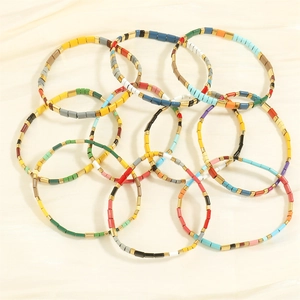 Detailed macro view of colorful Tila bead bracelets with gold alloy spacers on silk cloth