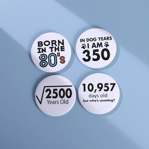 Detailed view of four round white tinplate badges with funny age-related quotes and slogans
