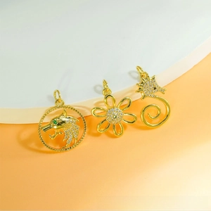 Close-up of golden pendants featuring a wolf head, flower, and seahorse with zircons