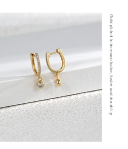 Macro detail of U-shaped gold plated earrings featuring sparkling micro-set round zircon