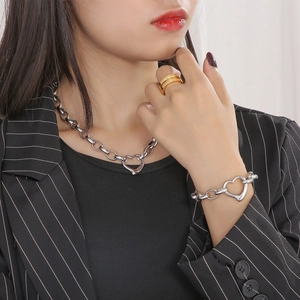 Close-up of model wearing silver heart pendant necklace and gold layered diamond ring