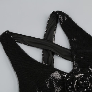 Detail of black sequined dress showing 3D floral accents and cross-strap neckline design