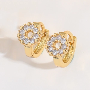 Macro detail of gold hoop earrings with star-shaped gear design and pavé cubic zirconia
