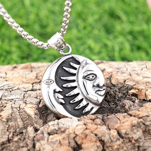 Vintage stainless steel sun and moon pendant necklace displayed on a textured tree bark