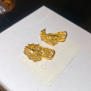 Détail de boucles d'oreilles vintage dorées avec motifs évidés et strass sur carte