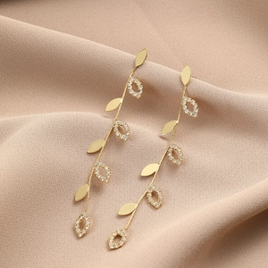 Detailed close-up of vine-shaped drop earrings with white rhinestones on fabric