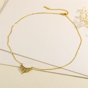 Detailed shot of gold wing pendant necklace with blue cubic zirconia on textured stone