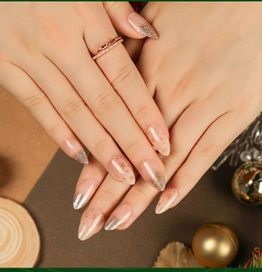 Detail of long almond nails with gold glitter gradient and Christmas snowflake designs