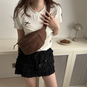 Brown corduroy crossbody waist bag with red heart pattern shown in an aesthetic setting