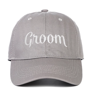 Detailed close-up of white Groom cursive embroidery on a grey cotton baseball cap