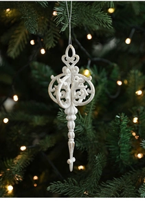 Close-up of vintage white Christmas tree ornament with gold glitter and hollow carved design