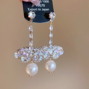 Detailed close-up of golden tassel earrings with sparkling rhinestones and white pearls