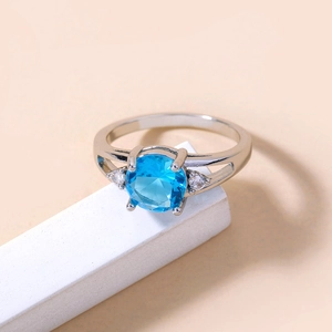 Detailed macro view of a silver ring with a deep blue round stone and zircon accents