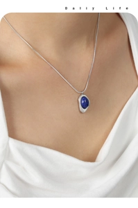 Close-up of matte silver triangle pendant with deep blue natural stone on model