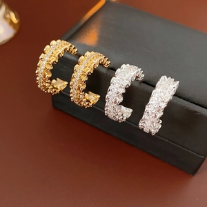 Macro shot of gold and silver C-shaped ear cuffs with micro-pave sparkling gemstones