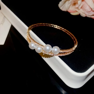 Détail d'un bracelet doré double couche avec perles blanches et pavé de cristaux
