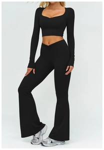 Dettaglio del crop top nero a maniche lunghe e dei pantaloni yoga con vita a V incrociata