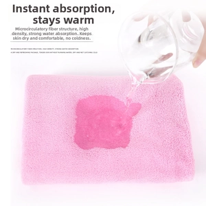 Absorbent pink coral fleece baby towel showing instant water absorption test