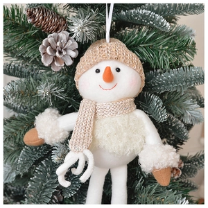 Close-up of a plush snowman ornament with gold knit hat on a festive Christmas tree branch