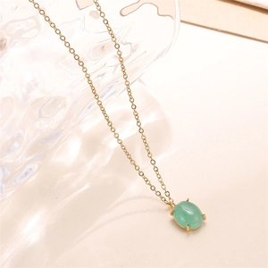 Close-up of 18k gold chain necklace featuring an oval green gemstone pendant