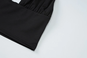 Close-up of black knitted fabric with elastic pleats and fine double-needle stitching details