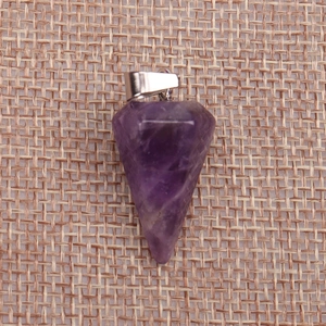 Macro shot of faceted purple amethyst crystal cone pendant on rustic woven linen