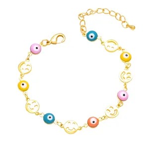 Golden bracelet with colorful evil eye beads and cutout smiley face charms on white background