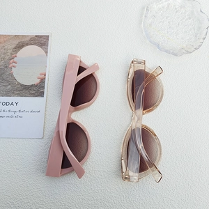 Flat lay detail of pink and tawny Y2K cat-eye sunglasses on a white textured background