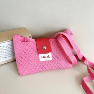 Detail of pink knitted crossbody bag with diamond texture and red canvas clasp