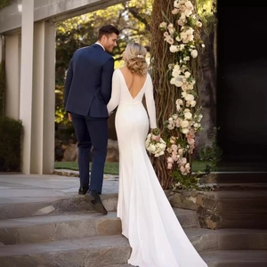 Robe de mariée sirène à manches longues avec dos en V profond et traîne longue sur l'escalier