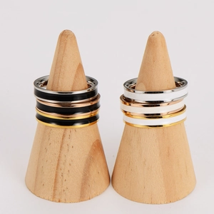 Dettaglio di anelli in smalto bianco e nero impilati su supporti in legno