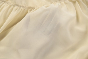 Close-up of semi-transparent beige chiffon fabric showing soft texture and sheerness