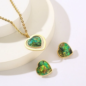 Detailed view of heart-shaped green resin pendants on gold titanium earrings and necklace