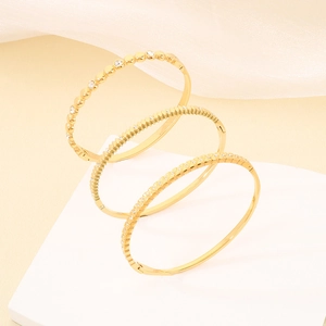 Vista dettagliata di tre bracciali rigidi in acciaio inossidabile dorato con strass