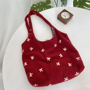 Detail of red plush tote bag with white bow embroidery and black-white checkered lining