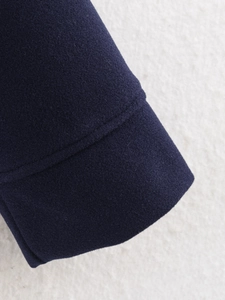 Detailed macro view of the navy blue wool coat cuff showing thick fabric and stitching