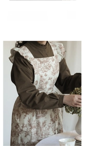 Detail of vintage French floral apron featuring elegant ruffle sleeves and brown pattern